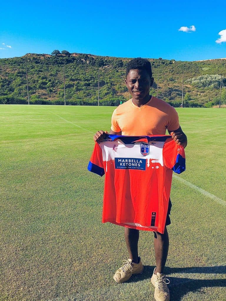 Tejan Brima holding his red, blue, and white jersey