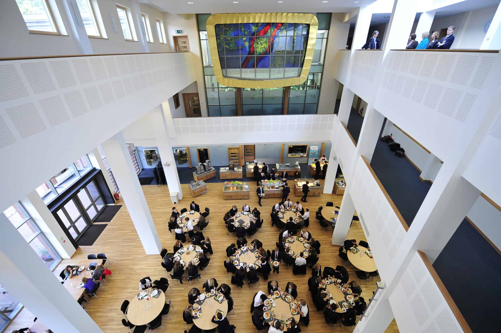 Dining hall filled with tables and students eating from an aerial view.